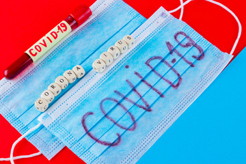 Coronavirus - COVID-19. Test tube with blood identified by the COVID-19 on blue red background....