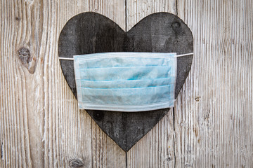 black wooden heart on white wood with mask