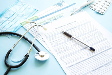 Diagnosis of coronavirus infection. At the doctor&rsquo;s appointment. A stethoscope, pills, a thermometer and a medical form on the doctor&rsquo;s table.
