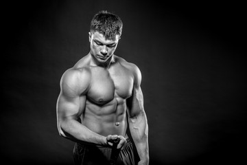 Fototapeta na wymiar Sexy young athlete posing on a black background in the Studio. Fitness, bodybuilding, black and white