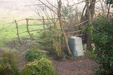 Compost bin in a backyard of a farmhouse on a misty winter morning