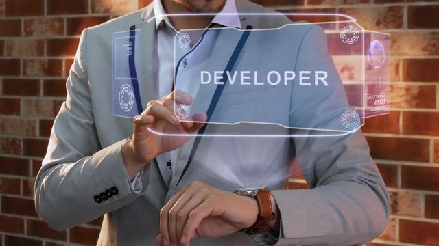 Unrecognizable businessman activates conceptual HUD holograms on smartwatch with text Developer. Man in jacket with holographic technology on wristwatch on background of brick wall