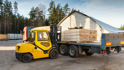 The machine loads the boards, lumber from the finished goods warehouse onto the truck