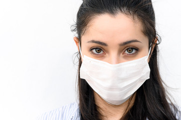 Close-up face of a beautiful girl in a protective medical mask on white background. Respiratory disease