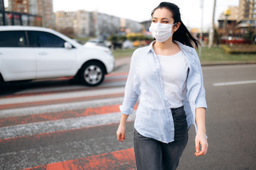 Sad girl walks through the city in a protective medical mask due to a respiratory infection