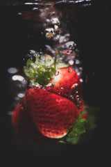 Blured starberrys falling into water, bubbles, isolated