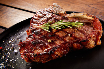 Grilled beef steak with rosemary, salt and pepper on black stone plate. Grilled striploin sliced...