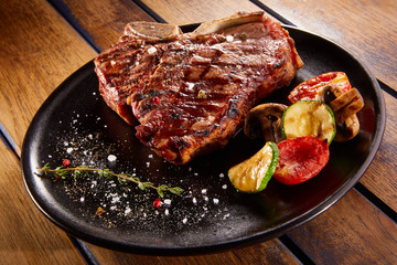 Grilled beef steak with rosemary, salt and pepper on black stone plate. Grilled striploin sliced...