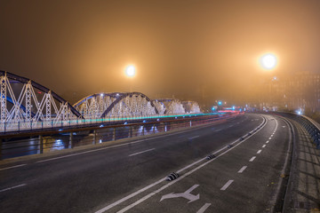 Steel bridge without people and cars in a night with haze, warm and cold colors
