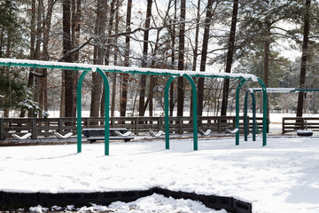 A swing set covered in snow after a winter snow storm in a public park.