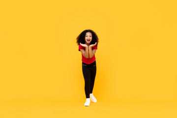 Fototapeta na wymiar Mixed race Afro girl in surprised excited gesture with hands open isolated on yellow background