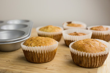 Little cupcakes freshly baked homemade muffins in a muffin pan and wooden board.