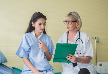 Senior female doctor meet the patient discussing consultation and making notes about symptom problem. Health care and client service in medicine concept.