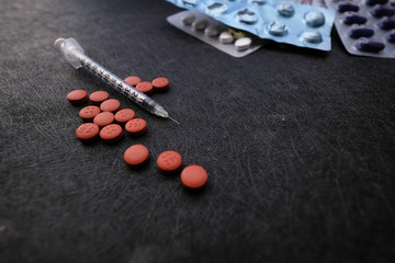 Fototapeta na wymiar close up of syringe and red color pills on black background 