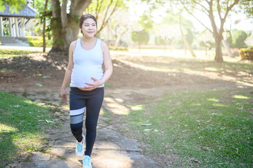 Portrait of young Asian pregnant woman walking and workout in the park. Conceptual of healthy and...