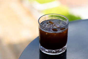 transparent glass of iced black coffee or americano on wooden table