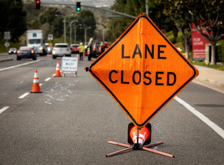 Lane Closed orange diamond shaped sign with work crew in distance
