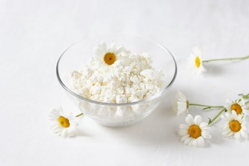 Homemade cottage cheese and cream in glassware. on a white background. Soft focus. Chamomile flowers as a symbol of rustic.  Copy Space