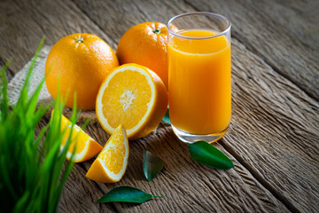 Close-up of Glass squeezed orange juice and fresh fruits ripe cut half, slice with green leaves on old wood vintage table. Breakfast food or beverage for the morning. Concept organic healthy natural.