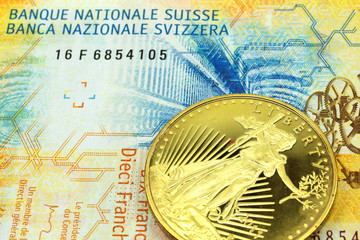 A macro image of a  yellow ten Swiss franc note with a gold coin.  Shot close up.