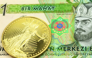 A macro image of a green one manat bill from Turkmenistan with a gold coin.  Shot close up.