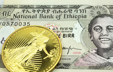 A macro image of a grey one birr note from Ethiopia with a gold coin.  Shot close up.