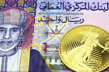 A macro image of a colorful one rial note from Oman with a gold coin.  Shot close up.
