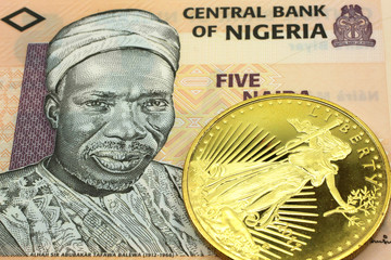A macro image of a peach colored Nigerian naira note with a gold coin.  Shot close up.