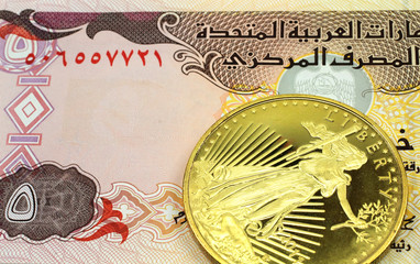 A macro image of a 5 dinar banknote from the United Arab Emirates with a gold coin.  Shot close up.