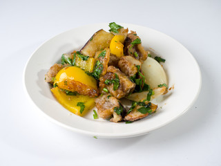 Hot eggplant and yellow pepper salad on a round white plate. Side view