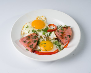 Fried sausage fried eggs on a white round plate. Side view