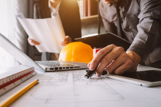Two colleagues discussing data working and tablet, laptop with on on architectural project at construction site at desk in office - Powered by Adobe