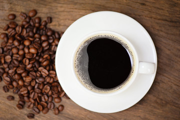 Coffee cup and coffee beans on table / black coffee in white mug on wooden background