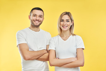 Young happy couple with arms crossed over yellow background