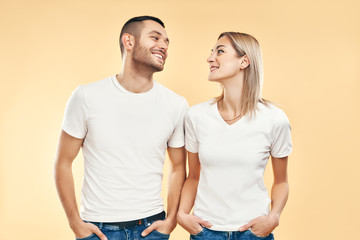 Young happy couple in love look to each other over beige background
