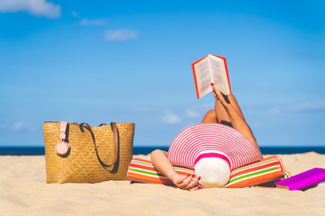 Women are sunbathing and read book on the beach there are bags and books on the side During the...