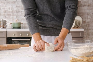 Man kneading dough in kitchen, closeup