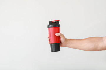 Naklejka premium Male hand with protein shake on light background