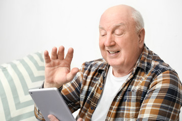 Portrait of elderly man with tablet computer at home