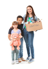 Female volunteer with donations for orphans and little children on white background