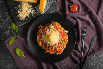 Plate with tasty pasta and cheese on dark background