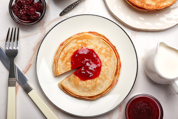 Stack of tasty sweet pancakes with jam on white table