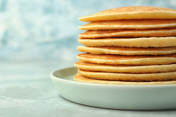 Stack of tasty pancakes on color background
