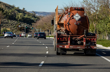Brown liquid fuel tanker truck on road on sunny morning