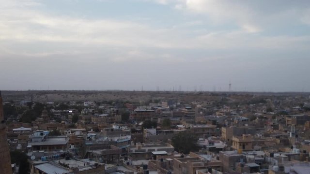 Low sun hyperlapse of an Indian city. The shot starts with a detail shot of birds on a rampart and then moves to a city scape.