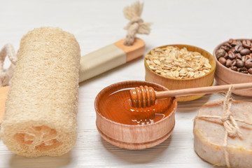 Bowl with honey, bast wisp and ingredients for scrub on white table