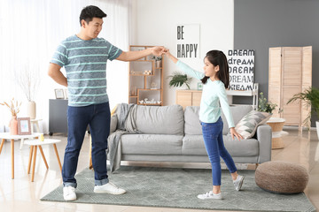 Obraz premium Happy Asian man and his little daughter dancing at home