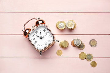Alarm clock and coins on wooden table. Time management concept