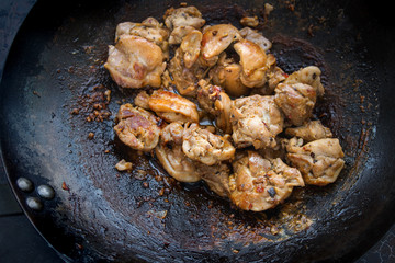 Chicken in a wok pan, Cooking process, Asian cuisine on dark background