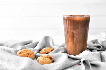 Glass of tasty iced coffee with cookies on table